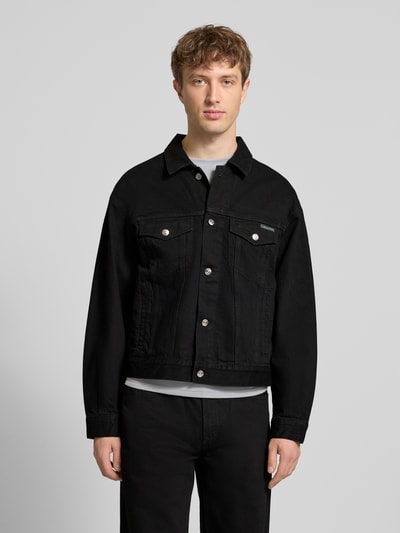 Męski model nosi Jeansjacke mit Brusttaschen und Label-Detail od Calvin Klein Jeans, czarna bawełna, krój regular fit, przód w całości,