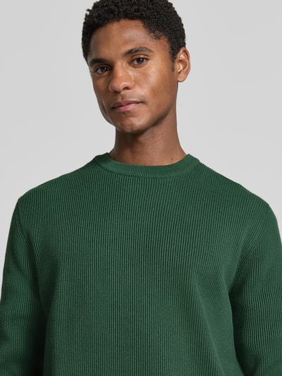 Männermodel trägt Slim Fit Strickpullover Baumwoll-Mix von Lindbergh in Dunkelgrün, gerippte Optik, Nahaufnahme Oberkörper.