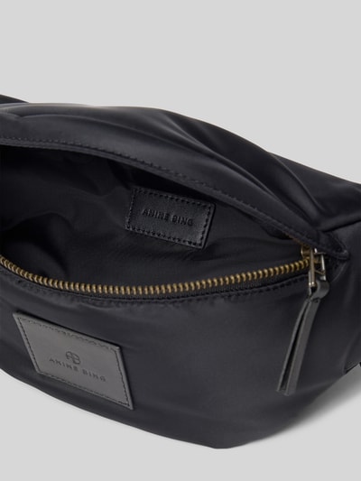 Produktfoto, schwarze Bauchtasche mit Klickverschluss von Anine Bing aus Satin, Label-Patch, Haupt- und Rückseitenfach mit Reißverschluss, 37x15x11 cm
