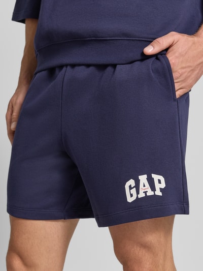 Männermodel trägt Straight Fit Shorts mit Logo-Stitching Modell 'Arch' von GAP in Dunkelblau, Baumwoll-Mix, Nahaufnahme Oberkörper.