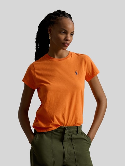 Modelka prezentuje T-shirt mit Label-Stitching von Polo Ralph Lauren z bawełny, krój regular fit, prążkowany okrągły dekolt, wyhaftowane logo, damski t-shirt w kolorze pomarańczowym, długość tyłu w rozmiarze S: 54 cm, widok na całą sylwetkę z przodu