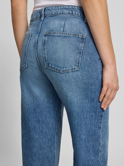 Vrouwenmodel draagt Wide Leg Jeans im Used-Look van Gina Tricot, blauwe denim, rechte vormen, ruw textuur, detailopname heup.