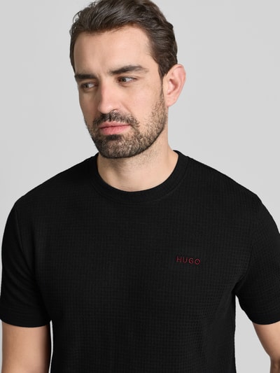 Männermodel trägt T-Shirt mit Label-Stitching Modell 'Austin' von HUGO, zwart, katoenmix, Regular Fit, ronde hals, Nahaufnahme Oberkörper.