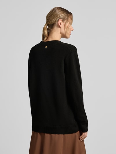 Frauenmodel trägt Relaxed Fit Cardigan aus reiner Wolle Modell 'Maglia Aperta' von Liu Jo White in Schwarz, Strick-Optik, Langarm, Ganzkörperansicht Rückansicht.