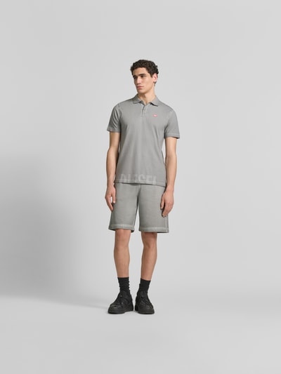 Männermodel trägt Regular Fit Poloshirt aus Baumwolle von Diesel in Grau mit Polokragen, Label-Details, Kurzärmelig, Ganzkörperansicht von vorne.