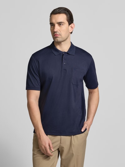Męski model nosi Regular Fit Poloshirt mit Brusttasche von Christian Berg Men, granatowy, bawełniany materiał-mix, krój regular fit, guzikowa listwa, kieszeń na piersi, długość tyłu w rozmiarze M 68 cm, całkowity widok z przodu.