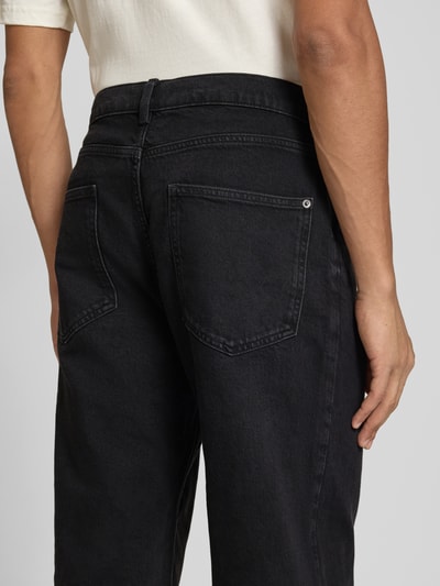 Męskimodel nosi Baggy Fit Jeans mit Knopfverschluss od REVIEW, czarny denim, 5 kieszeni, Szerokość w rozmiarze 32: 41 cm, Długość wewnętrzna nogawki 77 cm, Ganzkörperansicht Rückansicht.