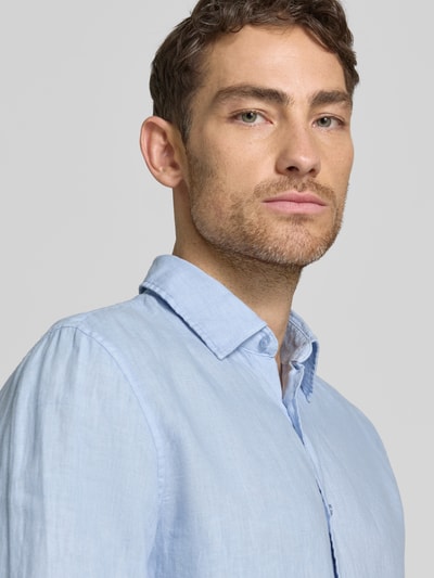 Männermodel trägt Leinenhemd mit Kentkragen van MCNEAL in lichtblauw, regular fit, puur linnen, knoopsluiting, detailopname bovenlichaam.