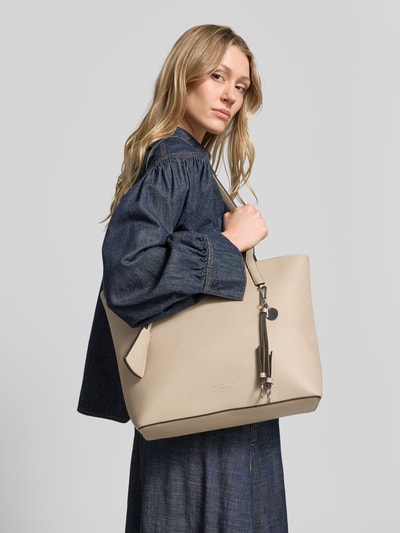 Frauenmodel trägt Shopper mit Label-Detail Modell 'LOHJA' von Seidenfelt in Beige mit strukturierter Oberfläche und Anhänger, Nahaufnahme Oberkörper. Damen Shopper mit Hauptfach mit Reißverschluss, Langen Tragegriffen, Reißverschlussfach innen, Breite 41 cm, Länge 29 cm, Tiefe 68 cm, Länge Schulterriemen 12 cm.