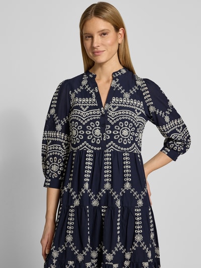 Vrouwenmodel draagt tuniekjurk met volantzoom en ajourwerk van Apricot, puur katoen, los model, midi-jurk, serafinohals, knoopsluiting. Nahaufnahme Oberkörper.