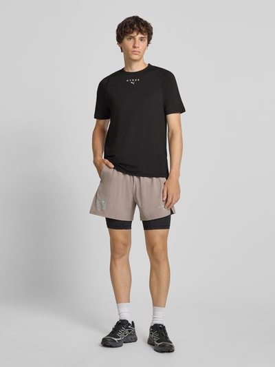 Männermodel trägt schwarzes Regular Fit Sport-T-Shirt mit Logo-Print Modell 'PWRMODE' von PUMA, Herren Sport-T-Shirt, Ganzkörperansicht von vorne.