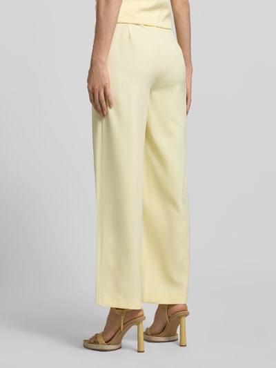 Männermodel trägt Relaxed Fit Hose mit gelegten Falten von Little Mistress, żółty materiał z domieszką stretchu, szerokość w rozmiarze 36: 33 cm, długość nogawki 75 cm, Ganzkörperansicht Rückansicht.