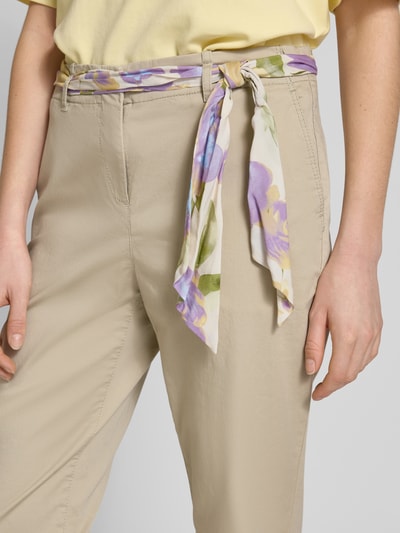 Frauenmodel trägt Slim Fit Chino mit Viskose-Anteil von Christian Berg Woman in Beige, mit Stoffband, Nahaufnahme Oberkörper.