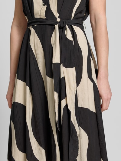 Frauenmodel trägt Hemdblusenkleid mit Bindegürtel Modell 'NIKITA' von Mango aus Viskose-Mix, Taillierter Schnitt, Midikleid, großflächiges schwarz-beiges Muster, Knopfleiste, Ärmel mit fixiertem Aufschlag; Nahaufnahme Oberkörper.
