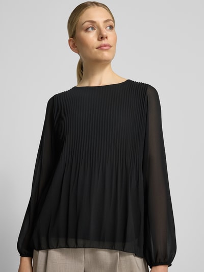 Vrouwenmodel draagt blouse met lange mouwen van viscosemix model 'Eva' van ZABAIONE, biezen, ronde hals, semi-transparante look, elastische mouwboord, onderhemd, zwarte kleur, textuur met plooien, voorkant bovenlichaam close-up. Ruglengte maat S: 62 cm, mouwlengte maat S: 60 cm.