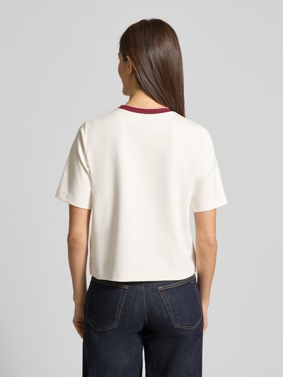 Frauenmodel trägt Regular Fit T-Shirt mit Strasssteinbesatz von Marc Cain, cremefarben, elastischer Baumwoll-Mix mit Modal-Anteil, Rundhalsausschnitt, Ganzkörperansicht Rückansicht.