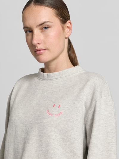 Frauenmodel trägt Relaxed Fit Sweatshirt aus Baumwoll-Mix von Emily Van den Bergh, hellgrau mit Statement-Stitching, Nahaufnahme Oberkörper.