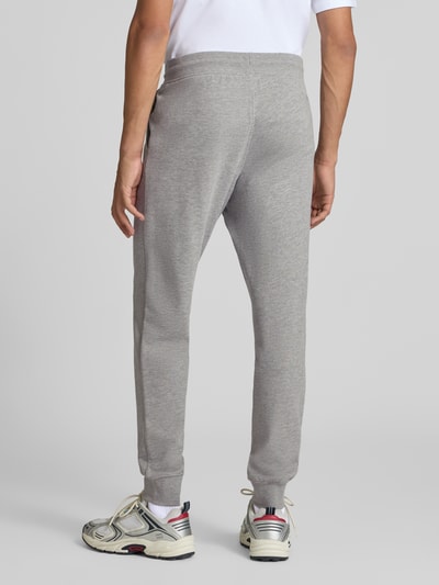 Mannelijk model draagt sweatpants met labelprint Model 'GORDON' van JACK & JONES in lichtgrijs met steekzakken, los model, elastische band met tunnelkoord, binnenbeenlengte bij maat M 77 cm, Ganzkörperansicht Rückansicht.