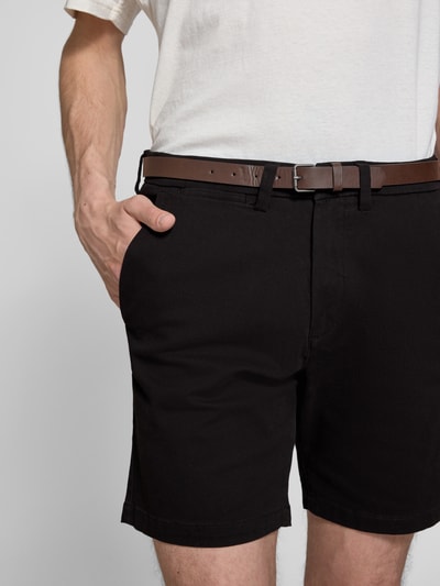 Männermodel trägt Straight Fit Shorts mit abnehmbarem Gürtel Modell 'Adam' von Jack & Jones, schwarze Baumwoll-Mix-Textur, Nahaufnahme Oberkörper. Elastischer Bund, Eingriffstaschen, Knopf- und Reißverschluss, Bundweite 40 cm, Innenbeinlänge 19 cm.