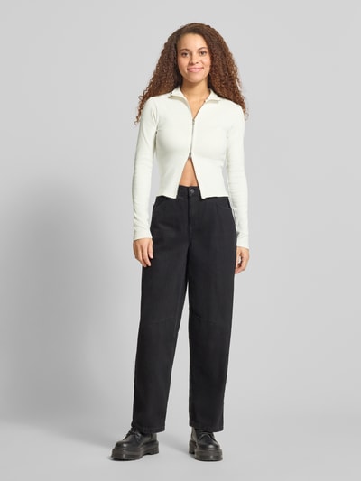 Frauenmodel trägt Slim Fit Jacke mit Stehkragen von Gina Tricot aus elastischem Baumwoll-Mix, Zweiwege-Reißverschluss, Ganzkörperansicht von vorne.
