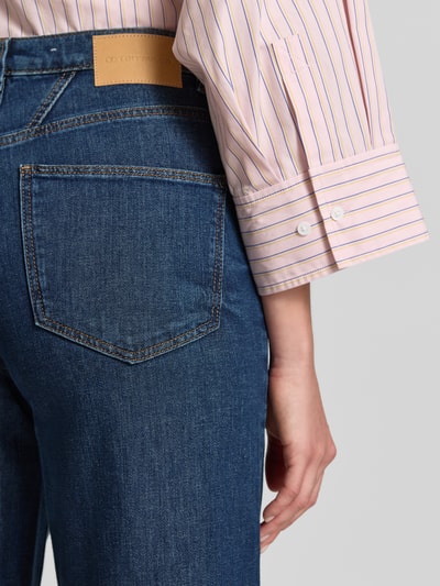 Vrouwenmodel draagt Loose Fit Jeans aus Baumwoll-Mix Modell 'MADINA WIDE' van Tom Tailor in denimlook met labelpatch, detailopname rug.