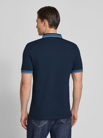 Männermodel trägt Regular Fit Poloshirt aus Baumwoll-Mix von s.Oliver RED LABEL in Dunkelblau mit Piqué-Struktur, Ganzkörperansicht Rückansicht.