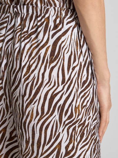 Frauenmodel trägt Stoffhose aus Viskose-Mix im Allover-Look Modell 'Mele' von FREE/QUENT, braun-weiße Muster, Nahaufnahme Hüfte, Kontext: Damen Stoffhose mit Tunnelzug, Wide Leg, Bundweite bei Größe S 39 cm, Innenbeinlänge 80 cm.