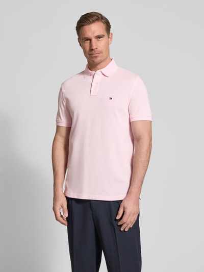 Męski model nosi Regular Fit Poloshirt aus Baumwoll-Mix von Tommy Hilfiger, efekt: jednolity kolor, krój regular fit, wyhaftowane logo, kołnierzyk polo, zapięcie na 2 guziki, krótki rękaw, wykończenie z rozcięciem, wykończenie materiału pika, mieszanka bawełny, widok całej sylwetki z przodu.