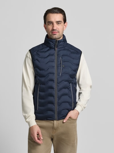 Männermodel trägt Regular Fit Steppweste mit Kapuze im Kragen von Tom Tailor, dunkelblau, unifarben, Label Patch, Ganzkörperansicht von vorne.