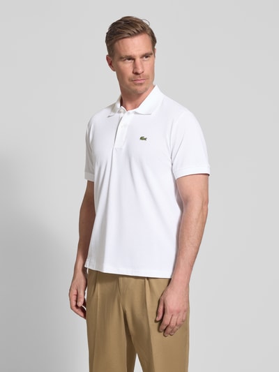 Männermodel trägt Regular Fit Poloshirt aus Baumwoll-Mix von Lacoste, Optik: Unifarben, Logo-Detail, Piqué, Kurzarm, Ganzkörperansicht von vorne.