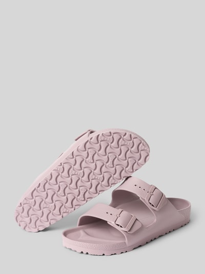 Produktfoto, Slides aus Leder mit Label-Prägung Modell 'ARIZONA EVA' von Birkenstock in zartem Rosa, profilierte Sohle, abgerundete Form, zwei breite Riemen mit Dornschließen, Absatzhöhe 4 cm, glatte und strukturierte Texturen.