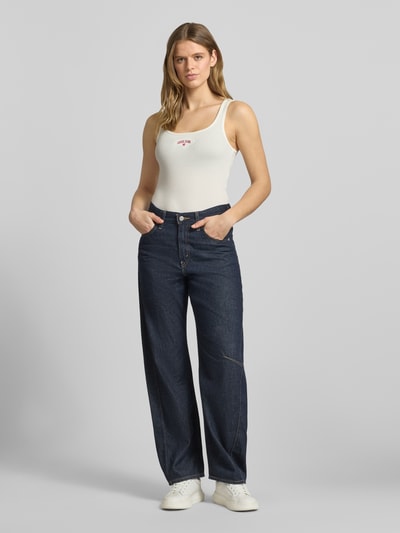 Vrouwenmodel draagt Tanktop in Ripp-Optik met Label-Stitching van Guess Jeans, mix van katoen en elastaan, slim fit, riblook, ruglengte maat S 53 cm, lichte kleur, strakke structuur, glad oppervlak, Ganzkörperansicht van voren.