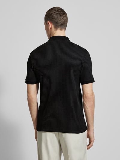 Męski model nosi Regular Fit Poloshirt mit Bio-Baumwoll-Anteil Modell 'FAVE' od SELECTED HOMME, czarny, tekstura prążkowana, krój regular fit, kołnierz polo, krótki zamek, krótkie rękawy, mankiety ściągaczowe, widok całej sylwetki z tyłu.