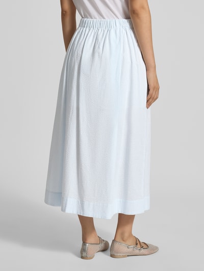 Frauenmodel trägt Ausgestellter Midi-Rock aus reiner Bio-Baumwolle Modell 'HANNAH' von Selected Femme mit Allover-Muster, Seersucker-Struktur, Regular Fit, elastischem Bund und seitlichen Eingrifftaschen, Ganzkörperansicht Rückansicht.