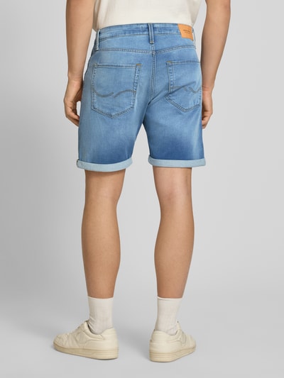 Männermodel trägt Regular Fit Jeansshorts mit Umschlag Modell 'RICK' von Jack & Jones, Used-Look, hellblauer Denim, Ganzkörperansicht Rückansicht.