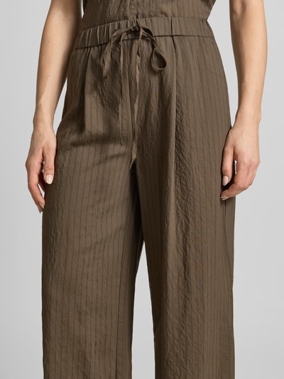 Frauenmodel trägt Stoffhose aus Viskose-Mix Modell 'TATU' von Mango in Braun, Wide Leg, elastischer Bund, Nahaufnahme Oberkörper.