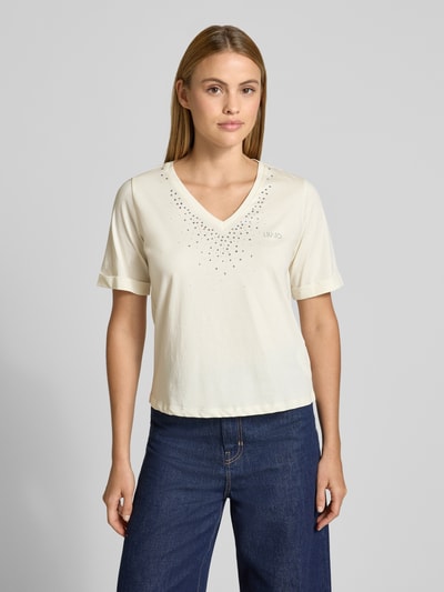 Frauenmodel trägt T-Shirt mit Strasssteinbesatz und V-Ausschnitt von LIU JO SPORT in Reine Baumwolle, Gerader-Schnitt, Logo-Print, Ganzkörperansicht von vorne.