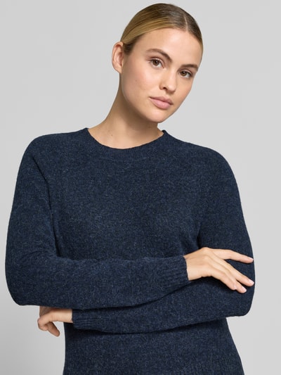 Modelka nosi granatowy sweter z okrągłym dekoltem Regular Fit Pullover mit Rundhalsausschnitt Modell 'DOFFY' od VERO MODA, damski sweter, zbliżenie na górną część ciała