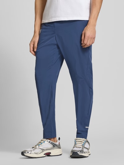 Mężczyzna nosi Trackpants mit elastischem Bund Modell 'EVARO' od Ellesse w kolorze niebieskim, materiał z domieszką stretchu, krój regular fit, widok całej sylwetki od przodu.