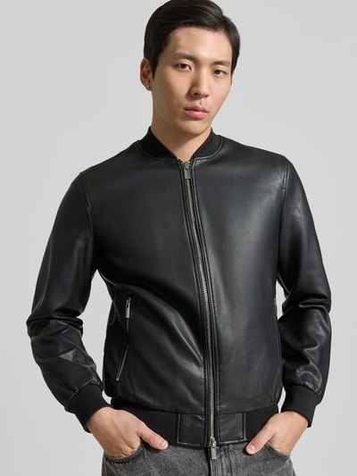 Männermodel trägt Bomberjacke in Leder-Optik mit Zweiwege-Reißverschluss von MARKUP, Material-Mix mit Viskose-Anteil, Regular-Fit, Stehkragen, schwarze Farbe, glatte Textur, Ganzkörperansicht von vorne.