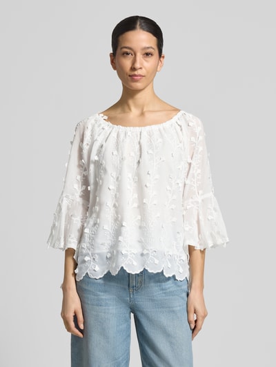 Kobieta modelka nosi Blusenshirt mit Spitze od Apricot, biała, z koronką, luźny krój, dekolt carmen, rękaw 42 cm, długość 51 cm, widok całej sylwetki z przodu.