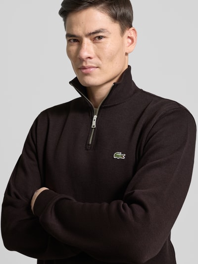 Männermodel trägt Regular Fit Troyer aus reiner Baumwolle von Lacoste in Unifarben mit Logo-Patch, Strick-Textur, Nahaufnahme Oberkörper.
