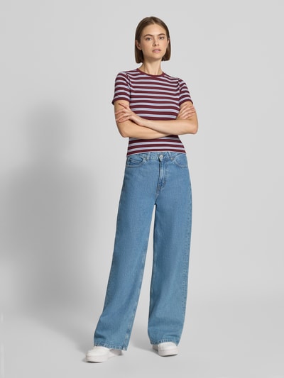 Frauenmodel trägt Slim Fit T-Shirt mit Viskose-Anteil Modell 'JUNE' von ONLY, gestreiftes Muster in Rot und Weiß, kombiniert mit blauer Jeans, Ganzkörperansicht von vorne, Damen T-Shirt von ONLY.