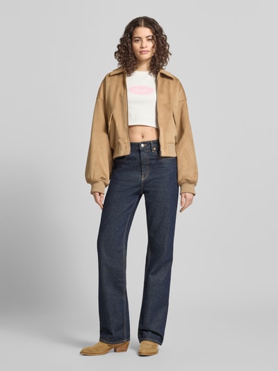 Frauenmodel trägt Cropped T-Shirt mit Logo-Print von ANOTHER COTTON LAB aus reiner Baumwolle, helle Farben, Ganzkörperansicht von vorne.