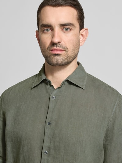Männermodel draagt Regular Fit vrijetijdsoverhemd uit puur linnen model 'RASH' van BOSS Orange, look: effen, labelprint, kentkraag, korte mouw, doorlopende knoopsluiting, materiaalverwerking: gevlamd garen, kleur olijfgroen, materiaal: puur linnen, Nahaufnahme Oberkörper.