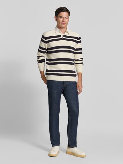 Männermodel trägt Slim Fit Poloshirt aus katoenmix von Lindbergh, Heren poloshirt, Polokraag, met lange mouwen, Ruglengte maat M 70 cm, Mouwlengte maat M 69 cm, gestreept in crème en donkerblauw, Ganzkörperansicht von vorne.