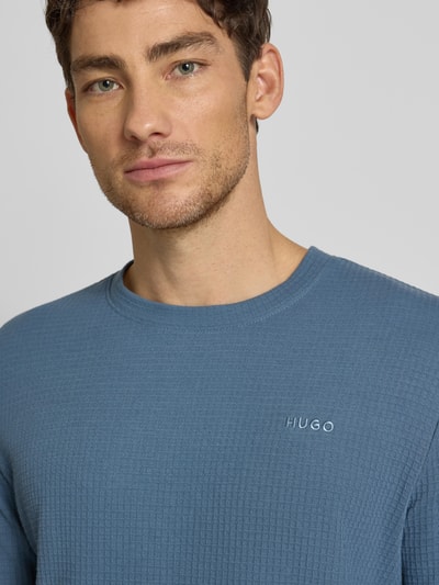 Männermodel trägt Regular Fit Pyjama-Oberteil aus Baumwoll-Mix Modell 'AUSTIN' von HUGO, Optik: Unifarben, Waffel-Struktur, Label-Stitching-Applikation, Rundhals, Langarm, Nahaufnahme Oberkörper.
