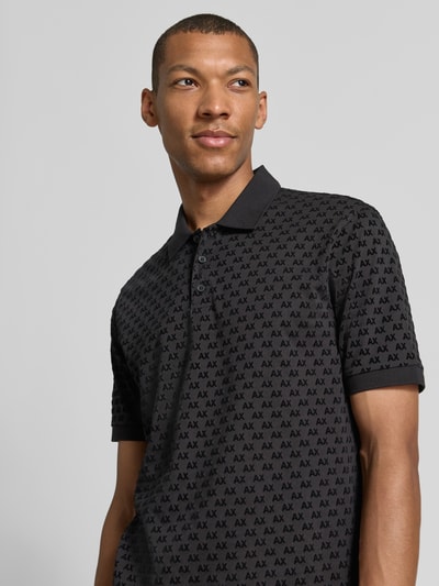 Männermodel trägt Regular Fit Poloshirt aus reiner Baumwolle von Armani Exchange mit Allover-Logo-Print in Schwarz, Nahaufnahme Oberkörper.