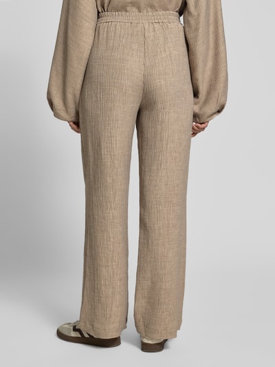 Frauenmodel trägt Stoffhose aus Viskose-Mix mit elastischem Bund von YAS, beige, Wide Leg, strukturierte Oberfläche, Ganzkörperansicht Rückansicht. Modell 'RINA', Stretch-Anteil, Bundweite 38 cm, Innenbeinlänge 78 cm, Größe 36.