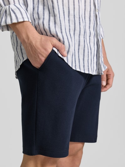 Männermodel trägt Shorts aus Baumwolle mit Strukturmuster von Christian Berg Men in Dunkelblau, Regular-Fit, Nahaufnahme Oberschenkel.